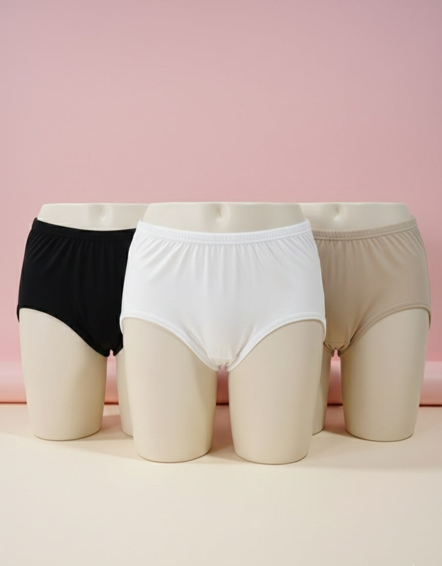 Three pairs of underwear in black, white, and beige on mannequin forms against a pink background.